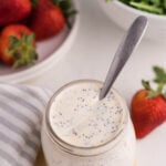 Paneras poppy seed dressing in jar with tomatoes and greens.
