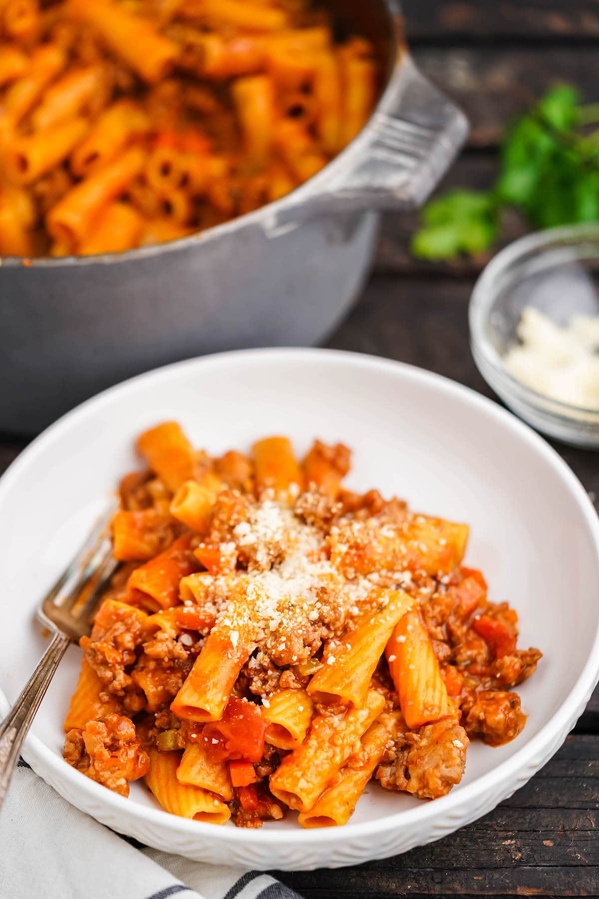 Rigatoni Bolognese in dish topped with parmesan cheese. 