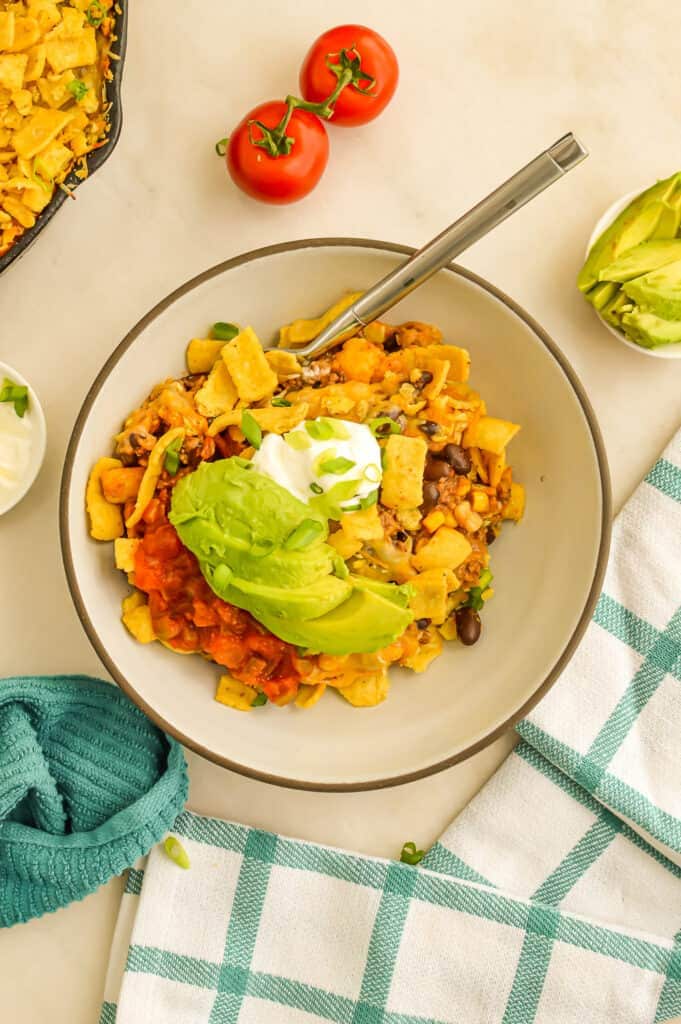 Walking taco casserole in bowl with fork. 