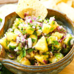 Pineapple salsa in bowl with chip.