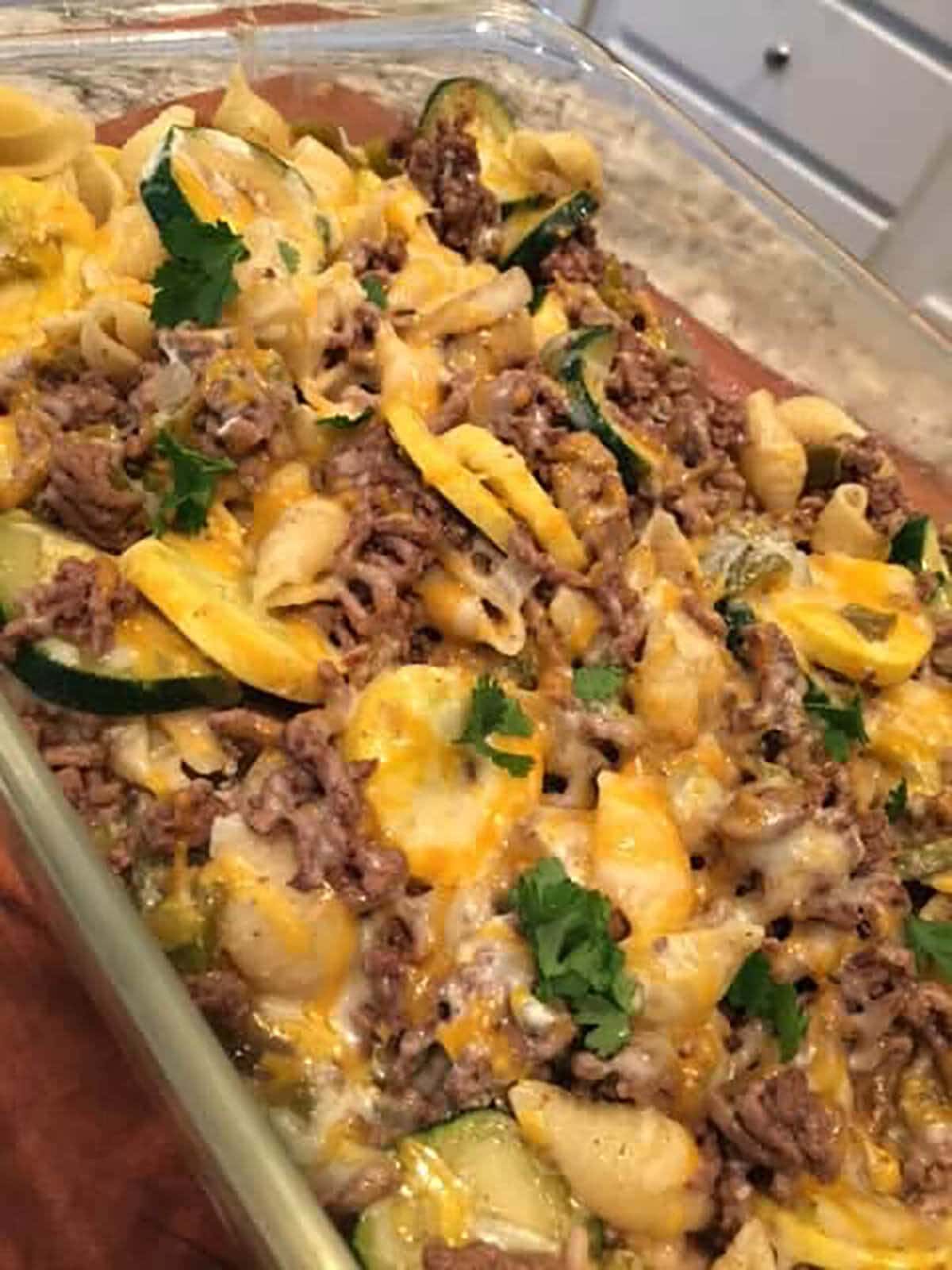Baked zucchini casserole topped with melted cheese in baking dish.