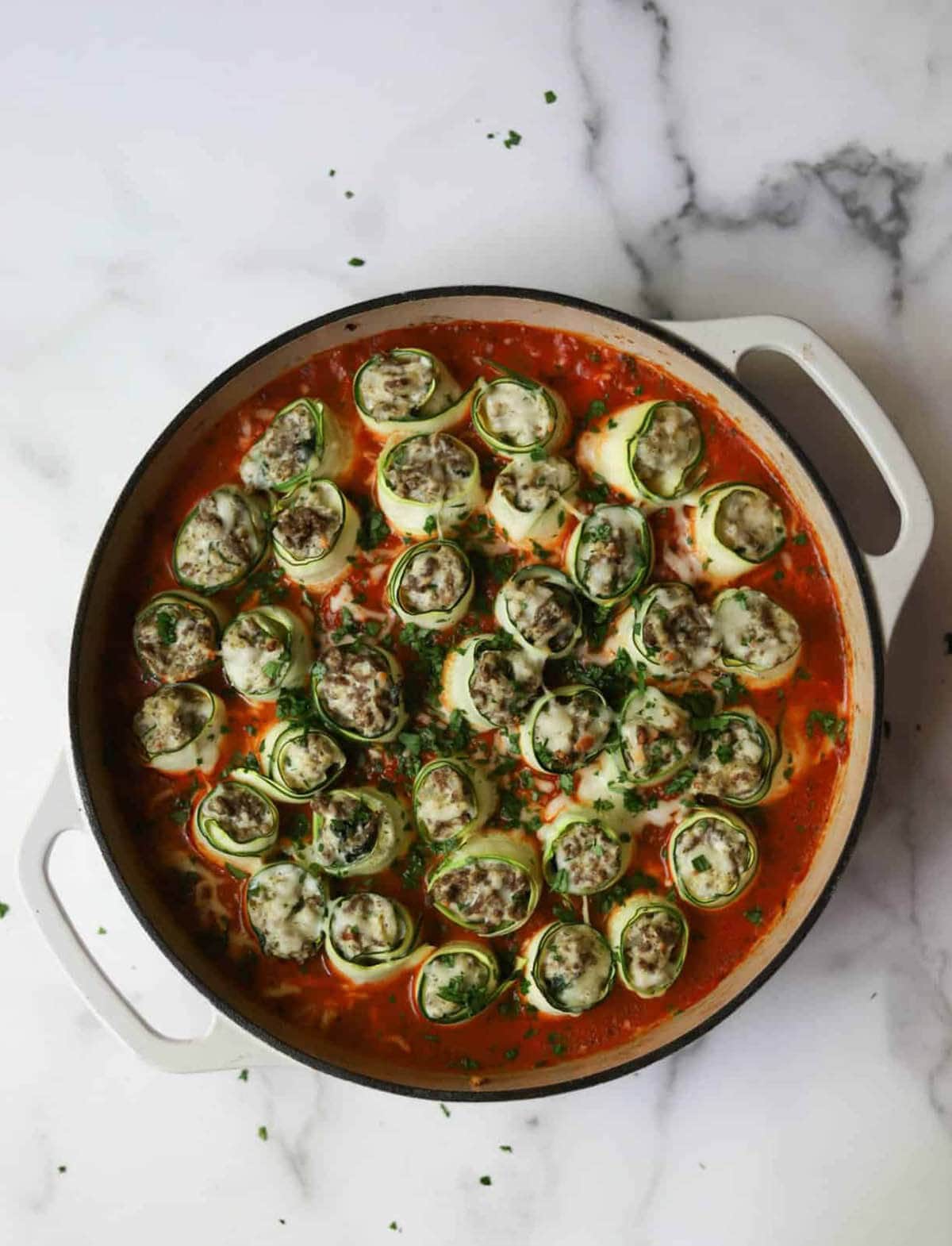 Zucchini rollups in baking dish with pasta sauce.