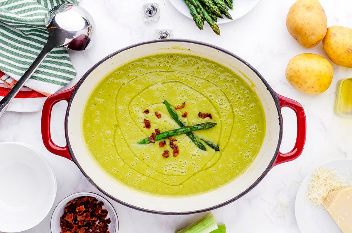 Pan filled with creamy asparagus soup, topped with crispy bacon.
