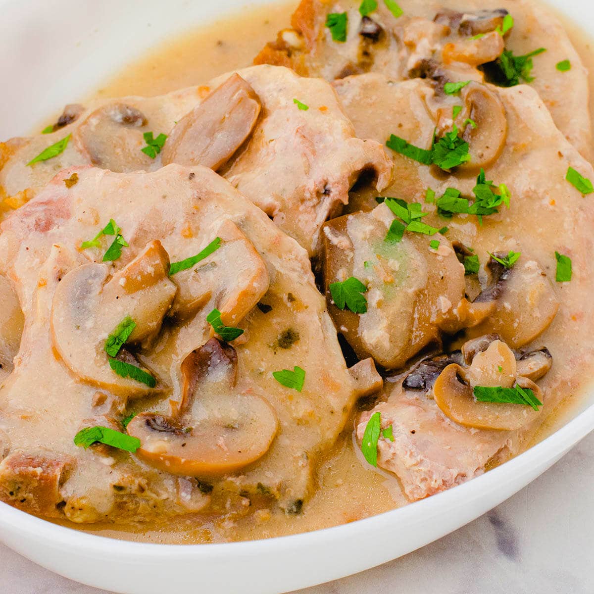 Crock pot pork chops with mushroom gravy in bowl.