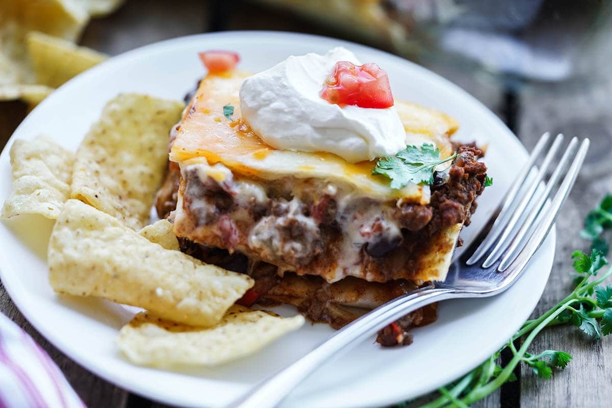 Layered Burrito Casserole on plate serve with chips.