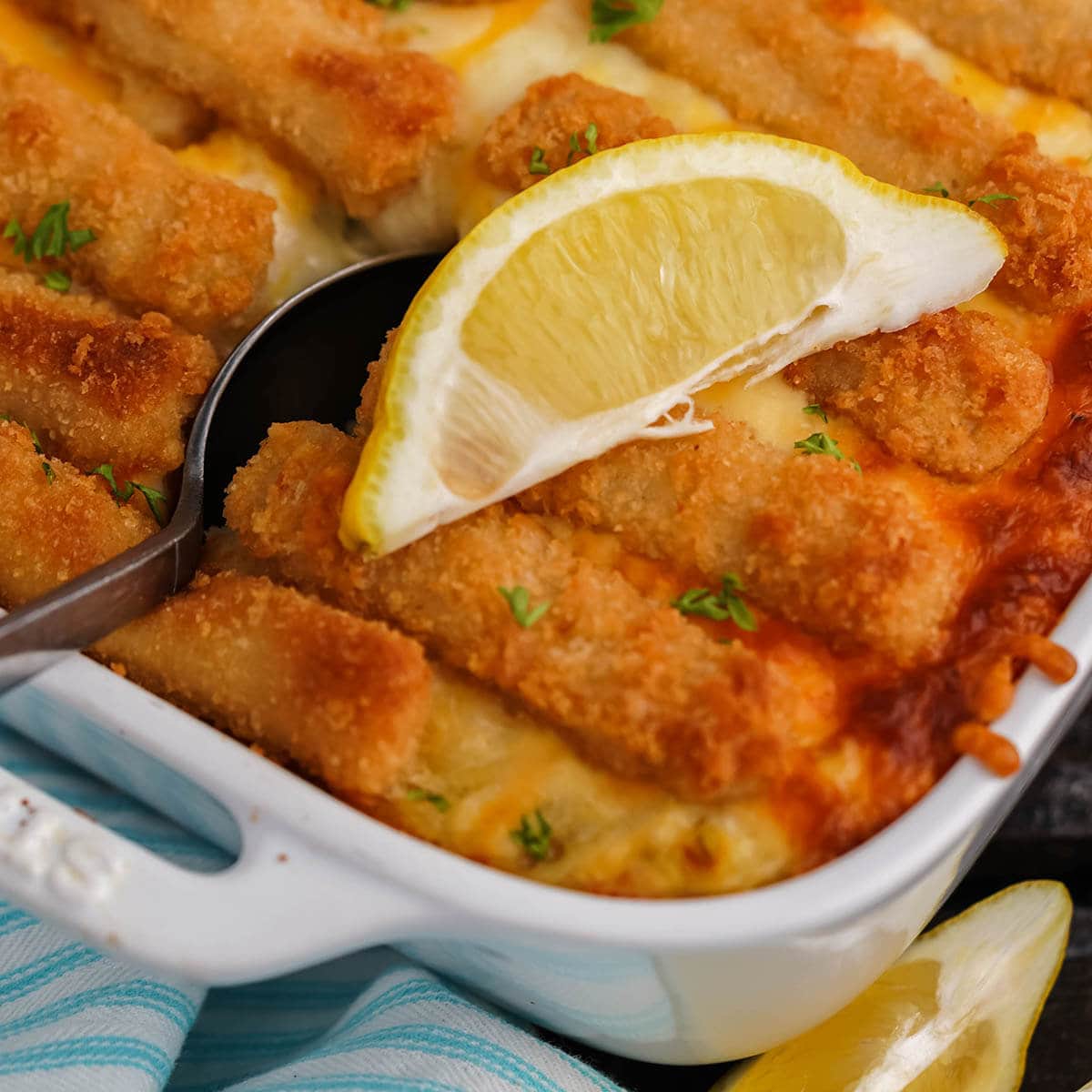Fishstick casserole in baking dish with serving spoon.