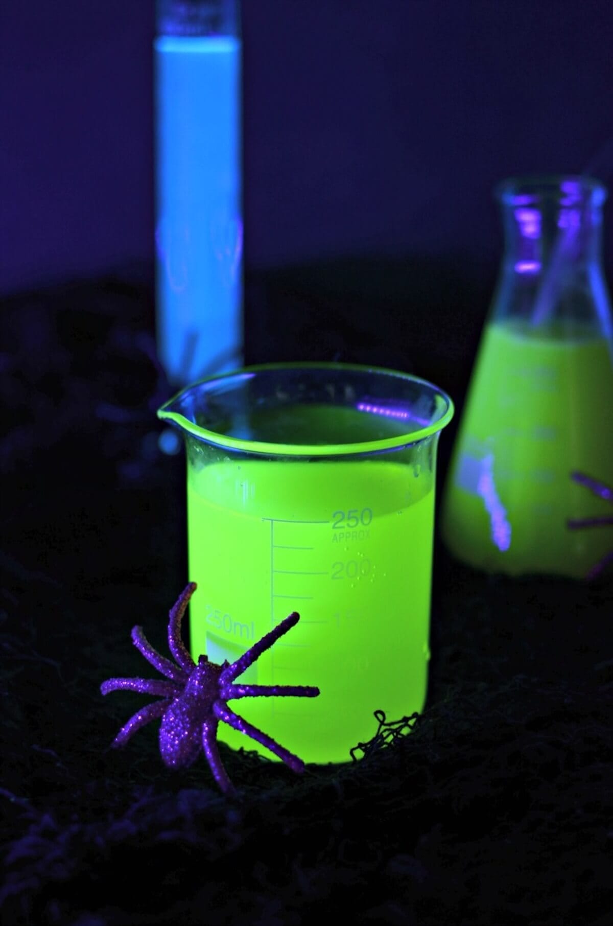 Glow in the dark green cocktail in science beaker glass.