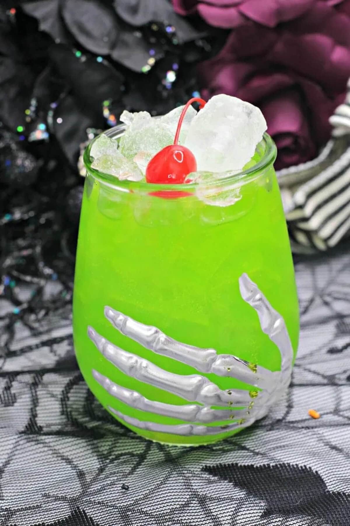 Lime green cocktail in glass with halloween decor.