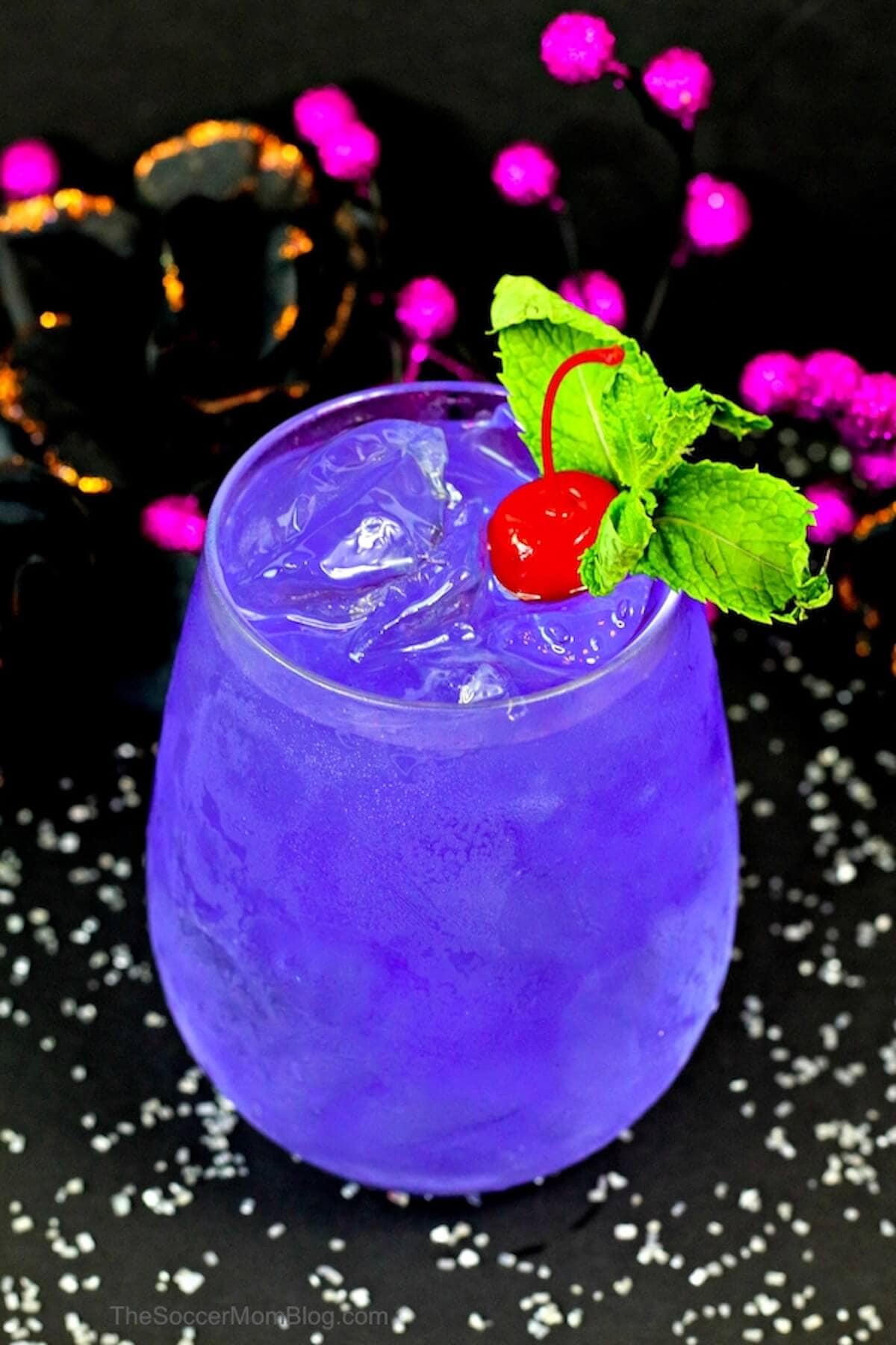 Purple cocktails topped with cherry and bright green mint for garnish.
