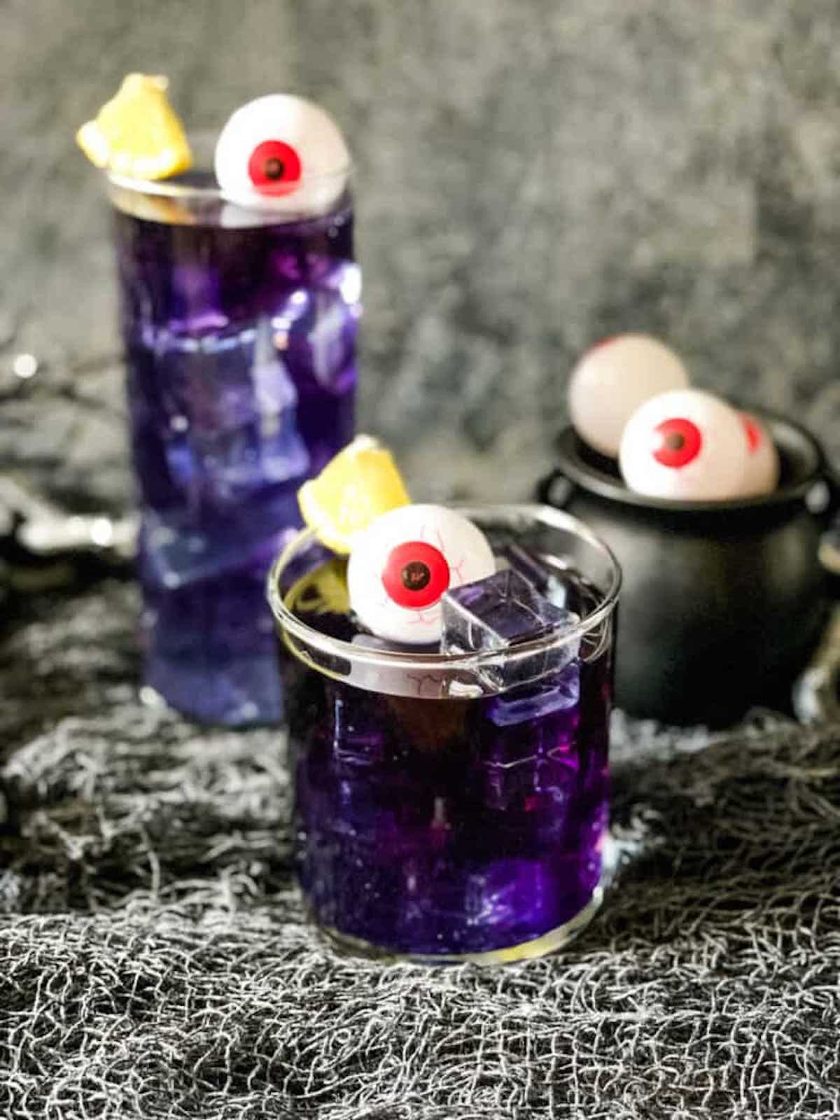 Purple people eater cocktails topped with candy eyes.