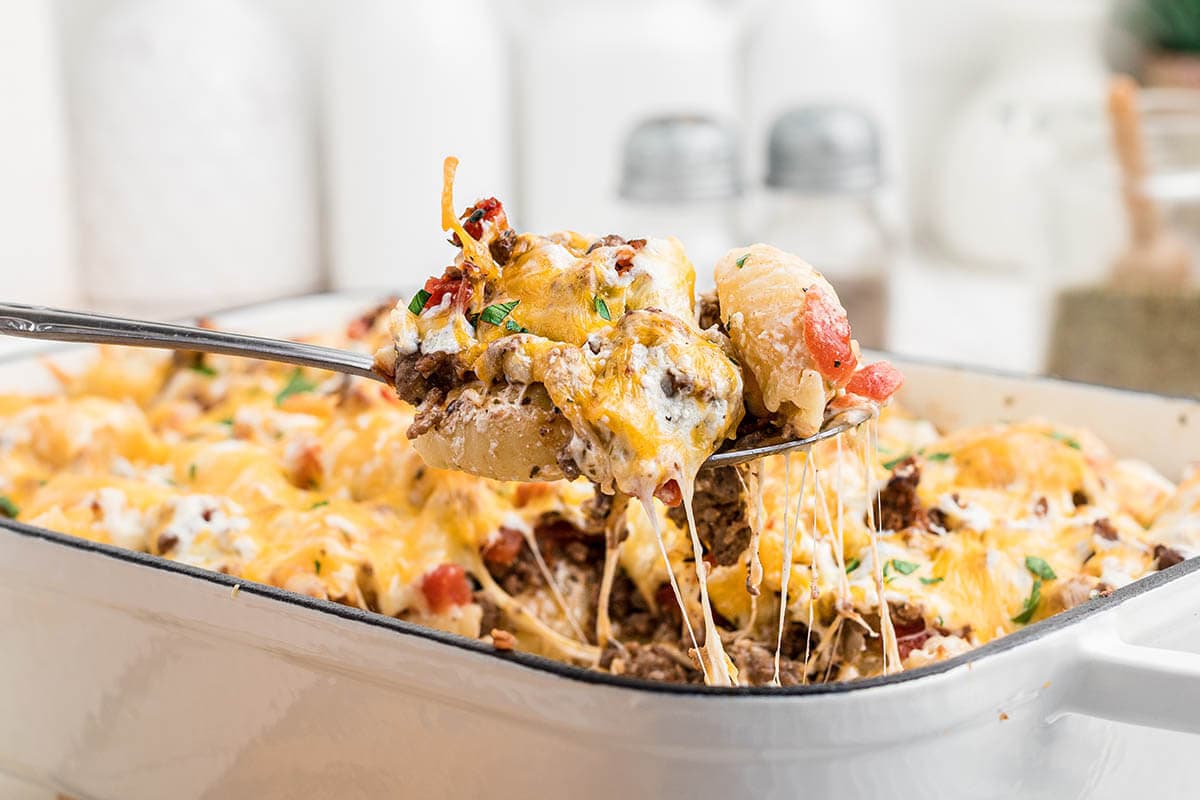 Cheesy hamburger casserole in baking dish with serving spoon.