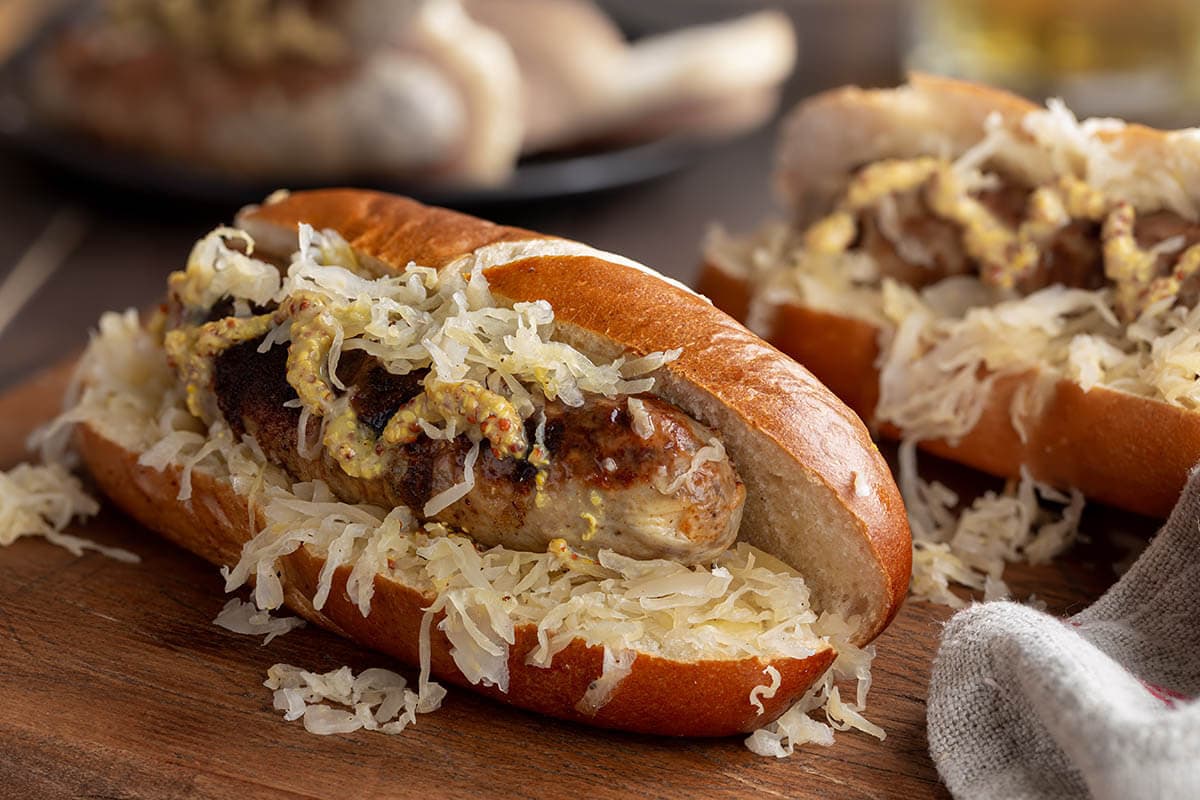 What to serve with brats, bratwurst in bun with sauerkraut and topped with German mustard.