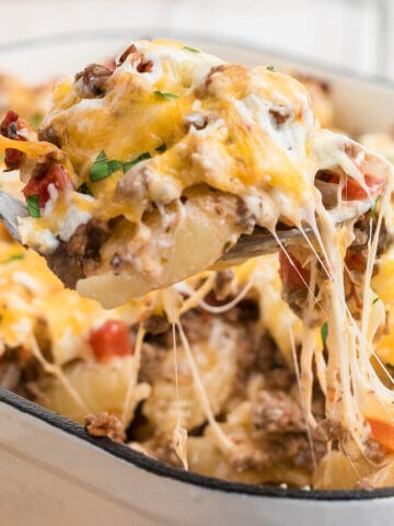 Cheesy hamburger casserole in baking dish with serving spoon.