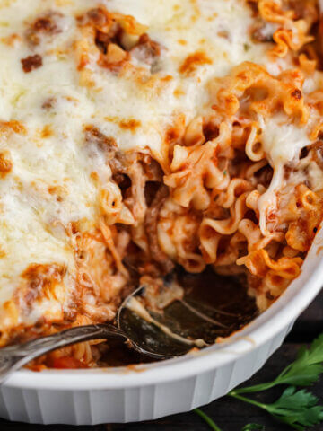 Lasagna in baking dish with spoon.