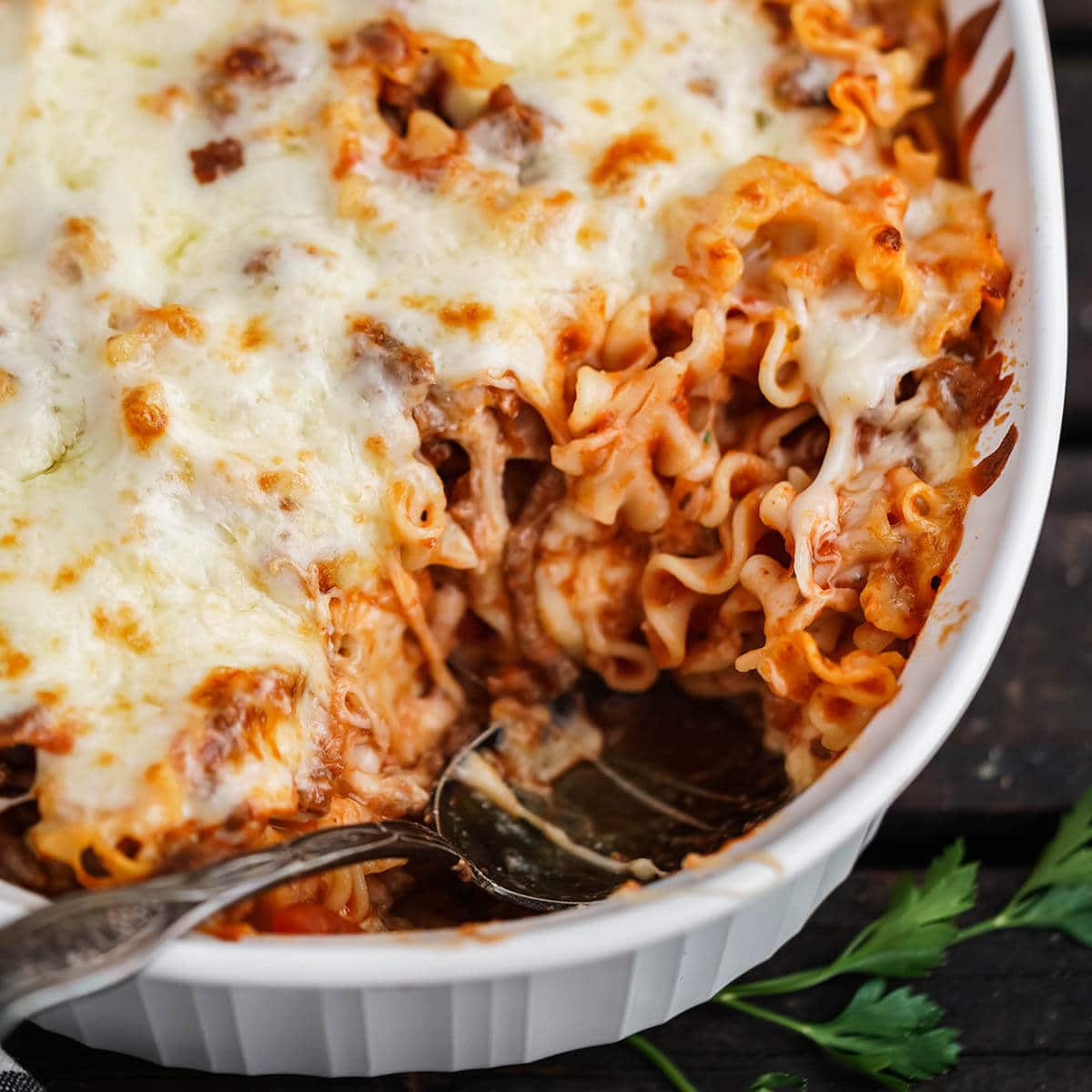 Lasagna in baking dish with spoon.