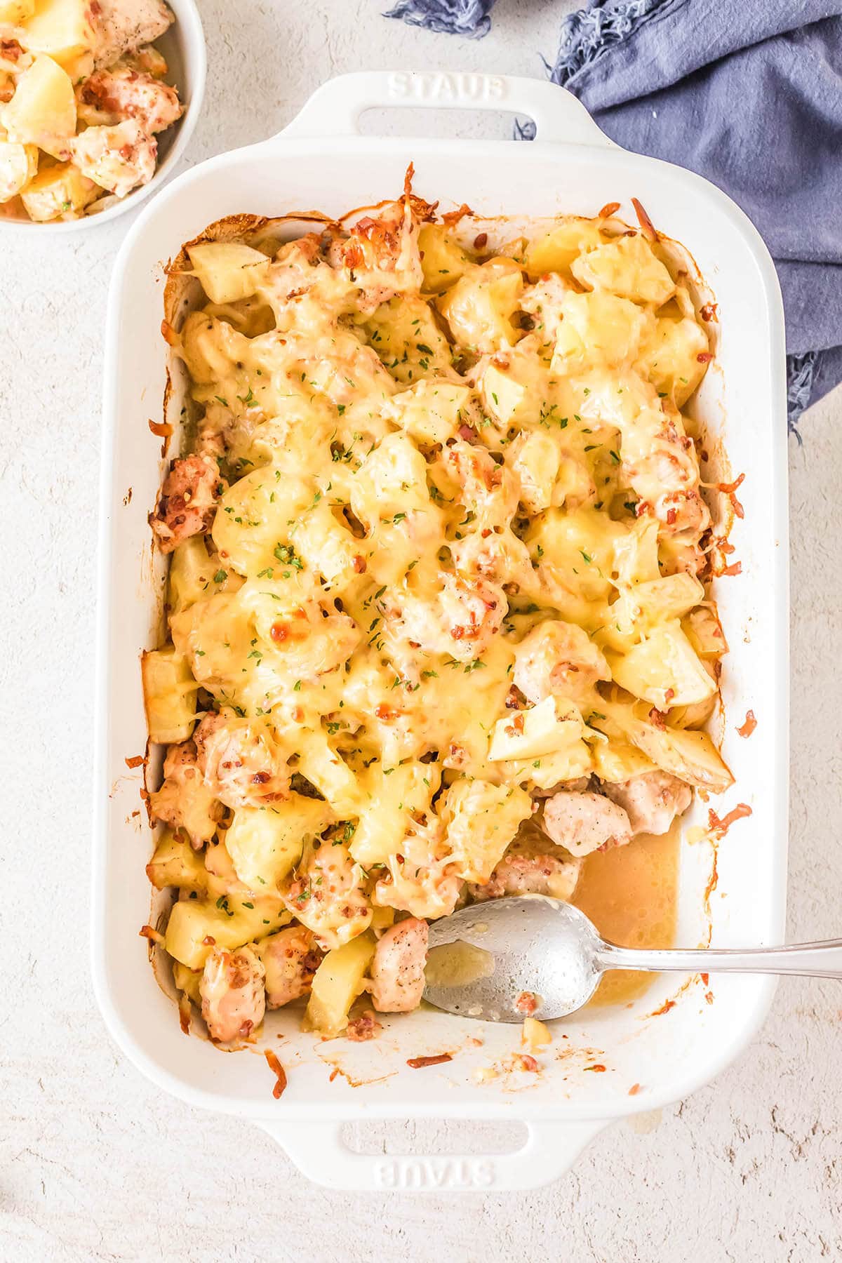 Chicken bacon ranch potato bake in casserole dish with serving spoon.