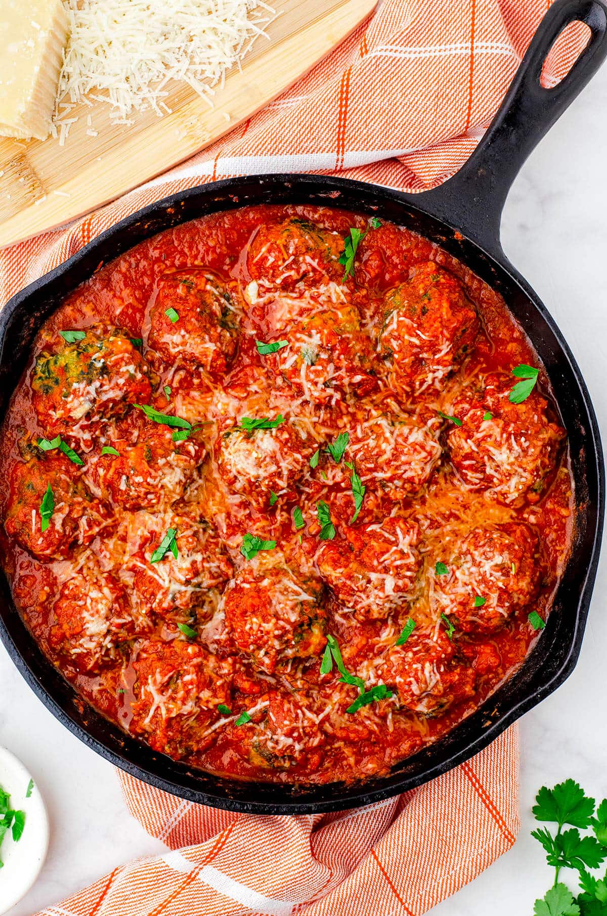 Meatballs in skillet covered with red sauce.