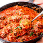 Baked Turkey Spinach Meatballs in skillet topped with red sauce and cheese.