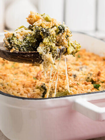 Broccoli casserole with crispy topping in baking dish with serving spoon.