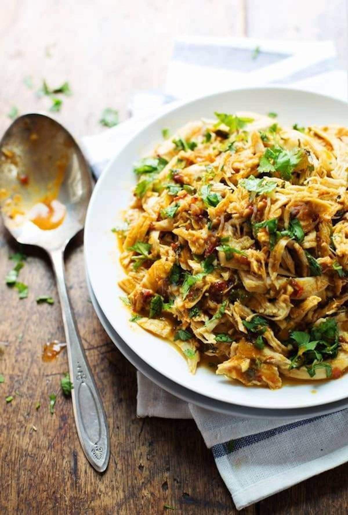 Spicy Chipotle shredded chicken in bowl with serving spoon.