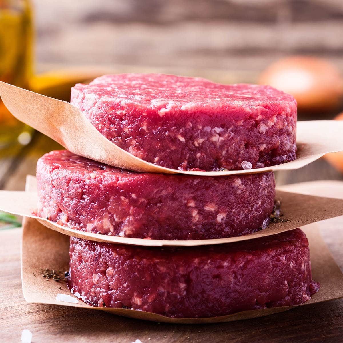 Organic raw ground beef, round patties for making homemade burger on wooden cutting board.