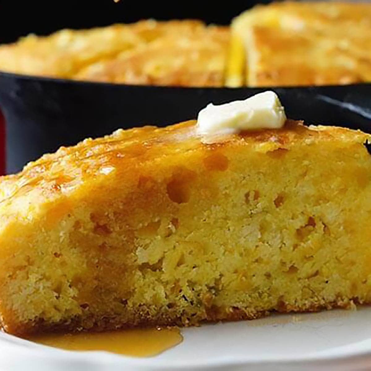 Jiffy Skillet Cornbread on plate topped with butter and honey.