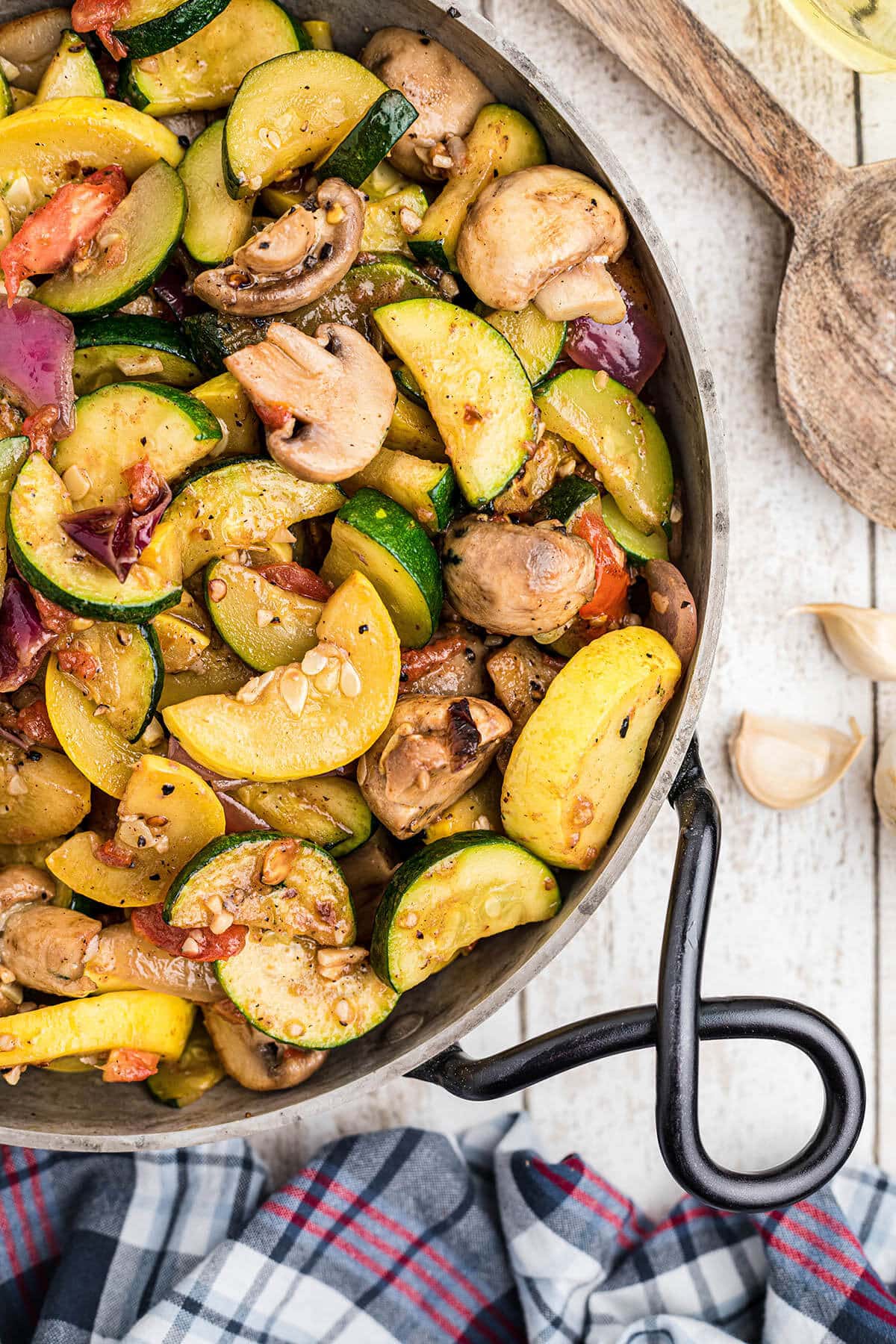 Roasted vegetables in fry pan with serving spoon.