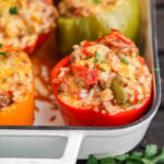 Baked bell peppers stuffed with meat and rice in baking dish.