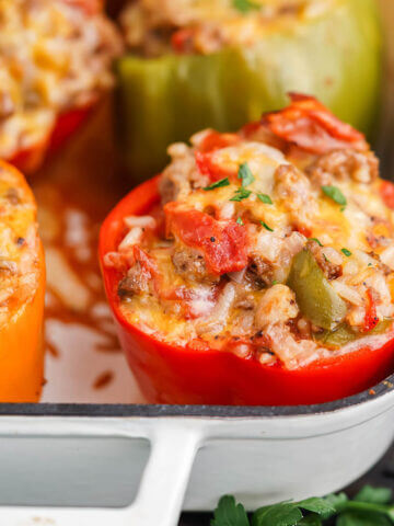Baked bell peppers stuffed with meat and rice in baking dish.