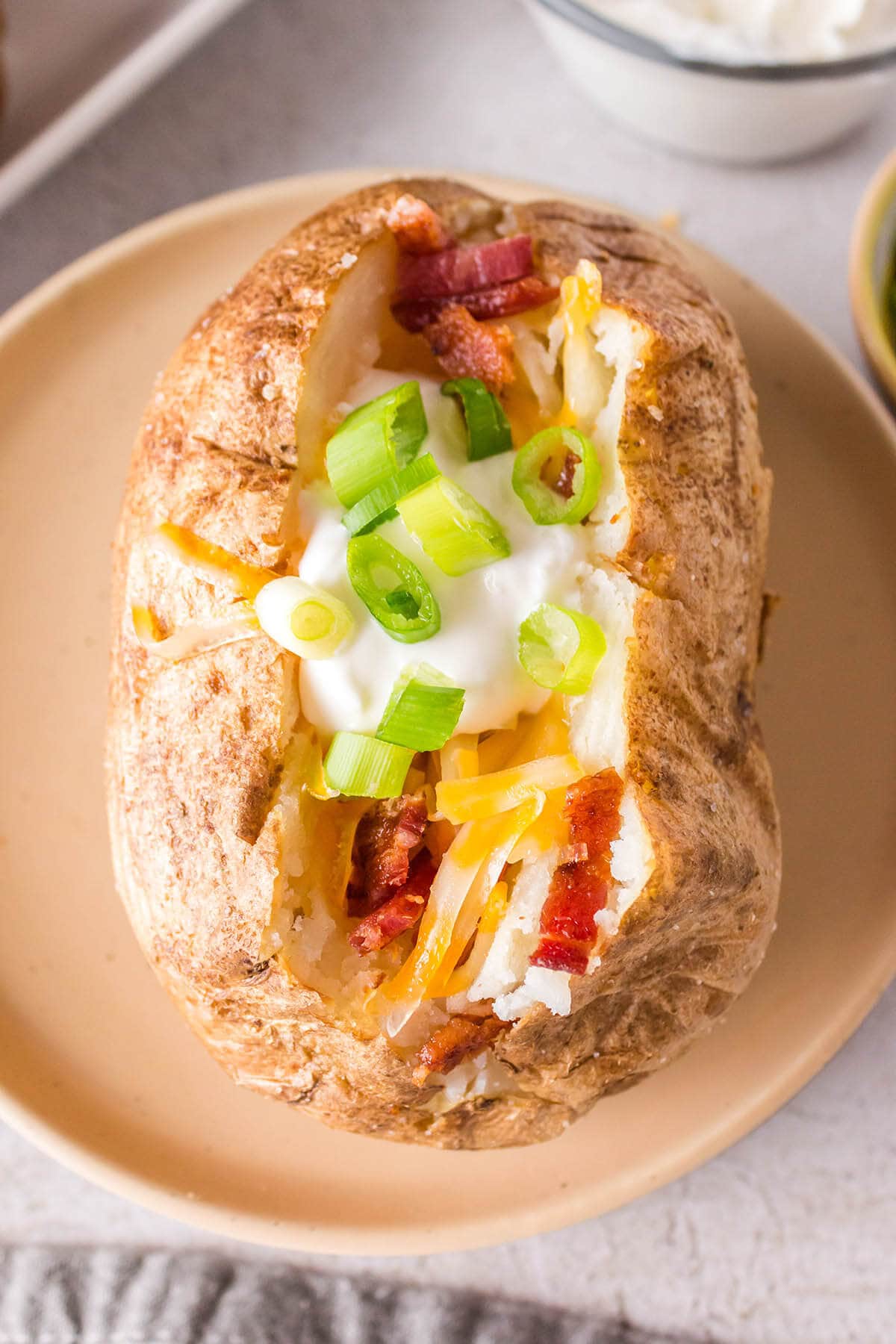 Baked potato on plate with all the fixings.