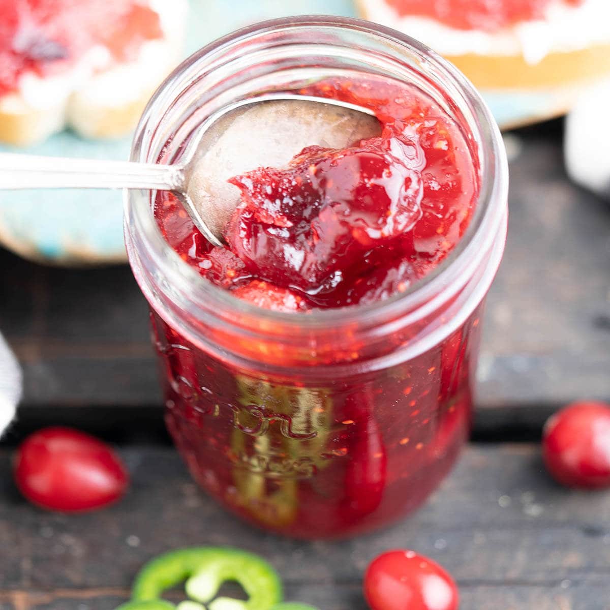 Cranberry Jalapeños Jam in jar with spoon.