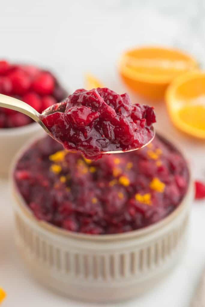 Cranberry Orange Sauce in a bowl with a spoon taking out a scoop to serve.