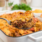 Layered Doritos Casserole in baking dish with serving spoon.