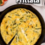 Frittata in a cast iron skillet with a spatula removing a slice.