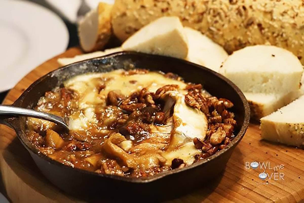 Brown sugar baked brie in cast iron skillet with spoon.