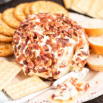 Cream cheese ball on plate surrounded by crackers.
