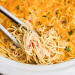 Crock Pot Chicken Spaghetti in slow cooker with tongs.