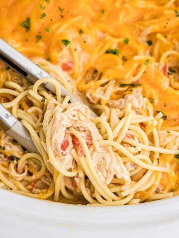 Crock Pot Chicken Spaghetti in slow cooker with tongs.