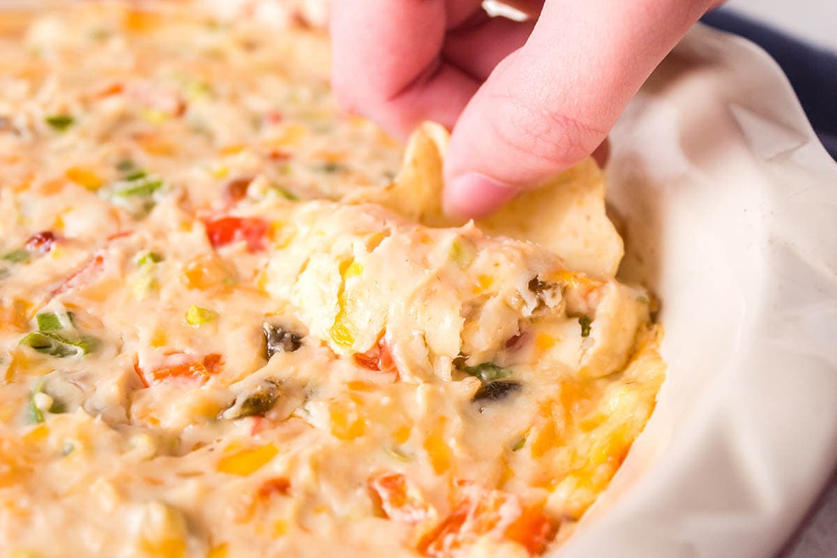 Cheesy hot dip in dish with chip for dipping.