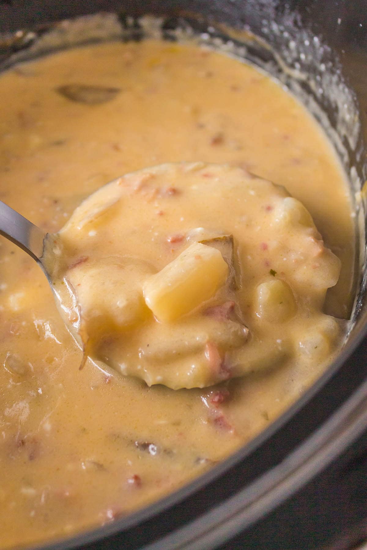 Slow cooker potato soup in crockpot with ladle.