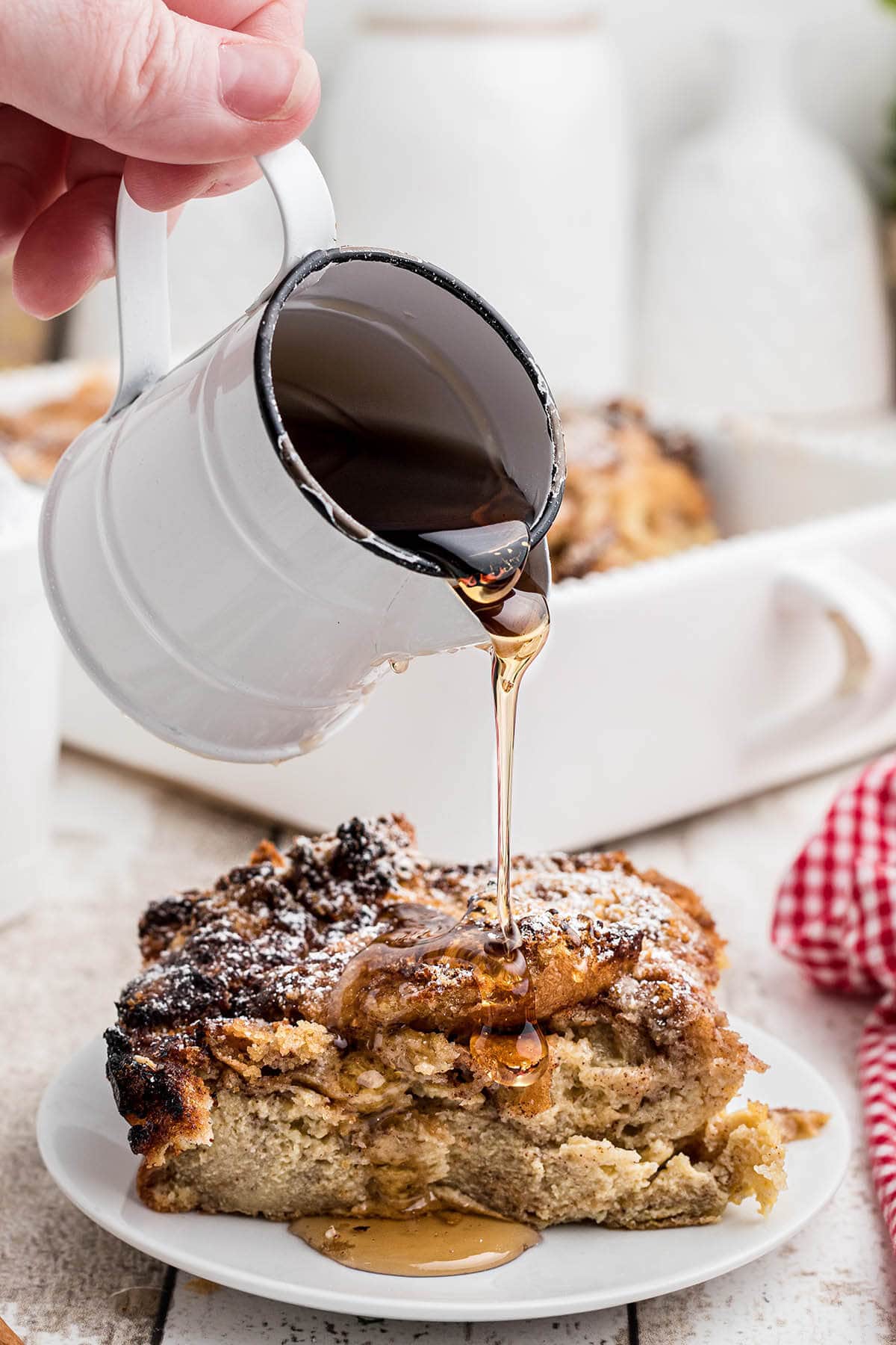 French Toast Casserole on plate with syrup being poured over it.