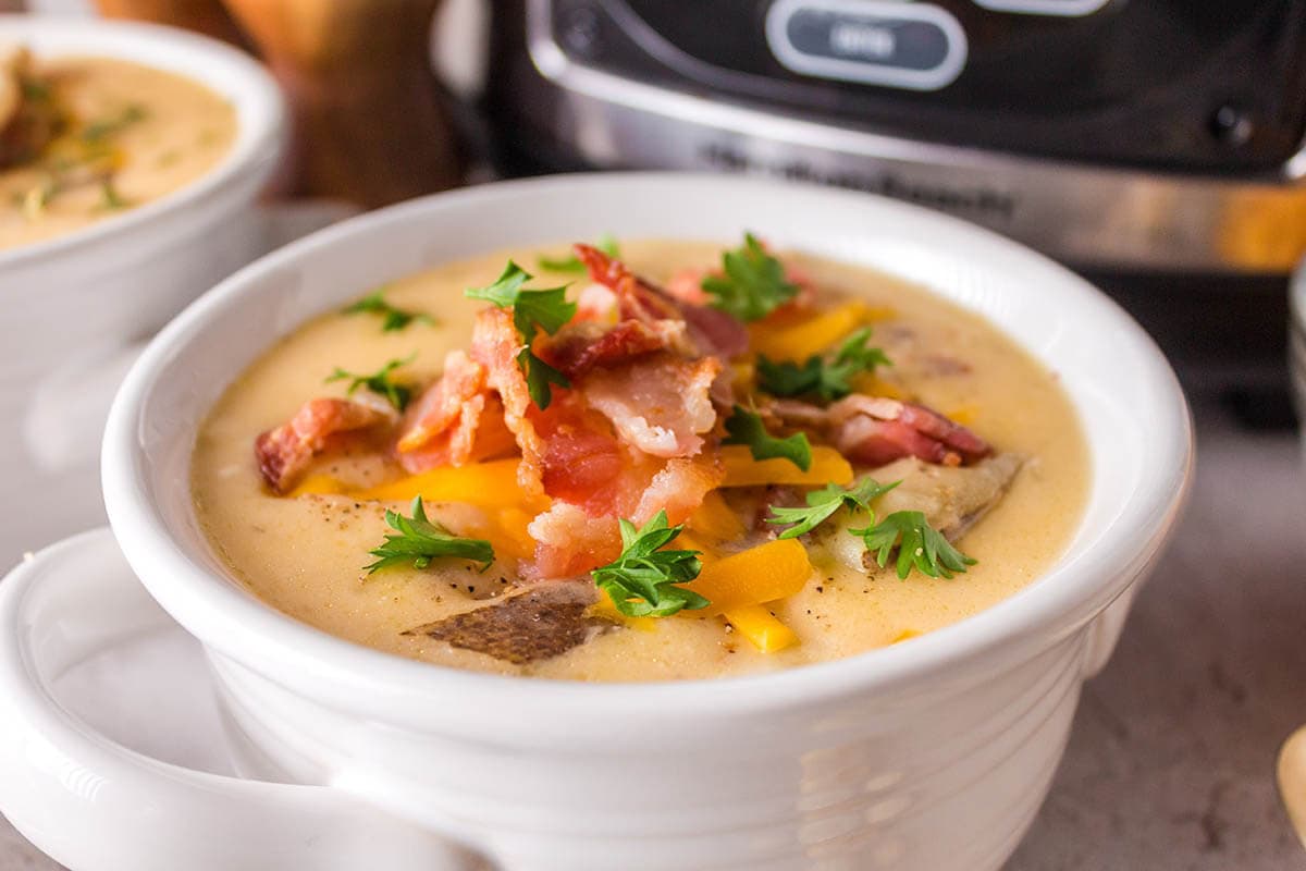 Bowl of slow Cooker Potato Soup topped with bacon and cheese.