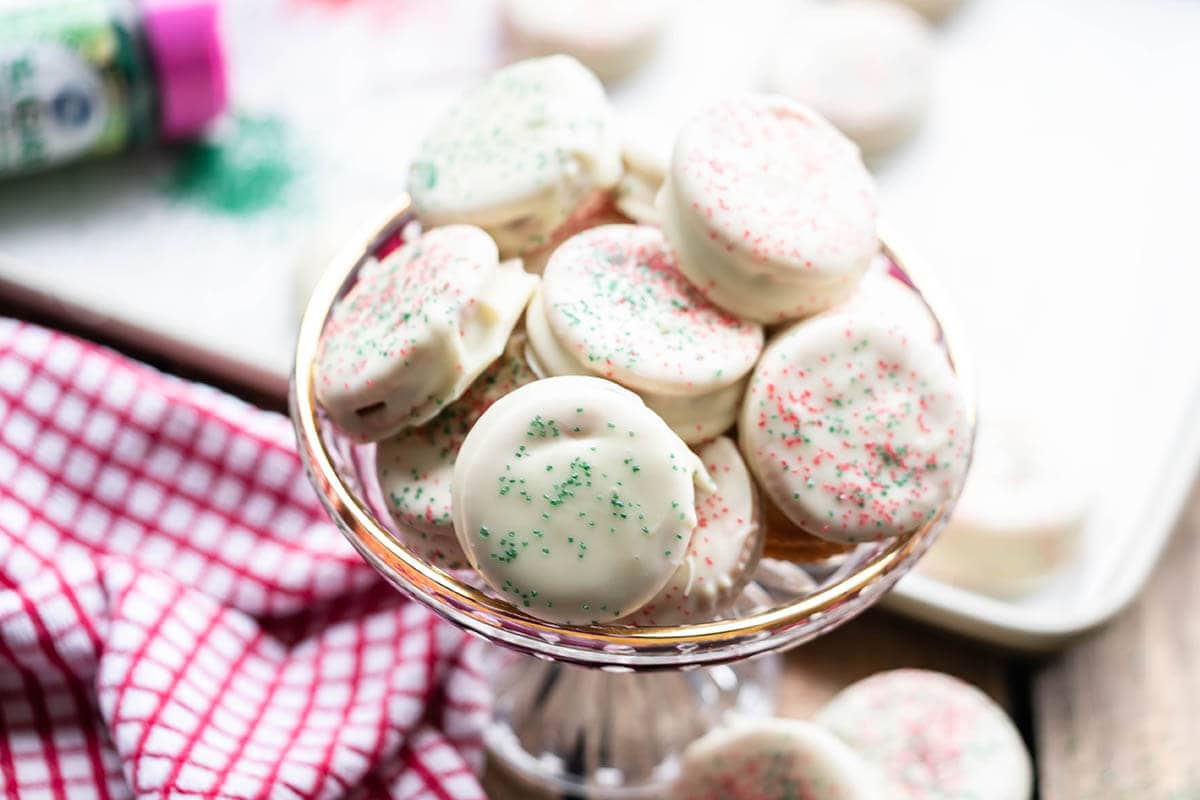 White chocolate dipped cookies decorated with sprinkles in pretty bowl.