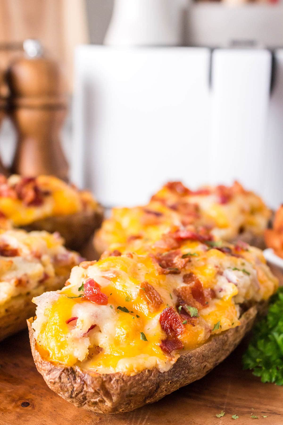 Twice baked potatoes on platter in front of an air fryer.