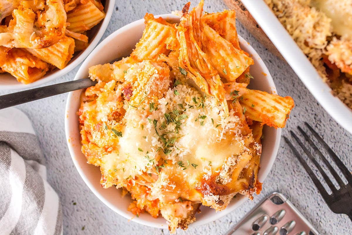 Bowl of cheesy chicken parmesan pasta in dish with fork.