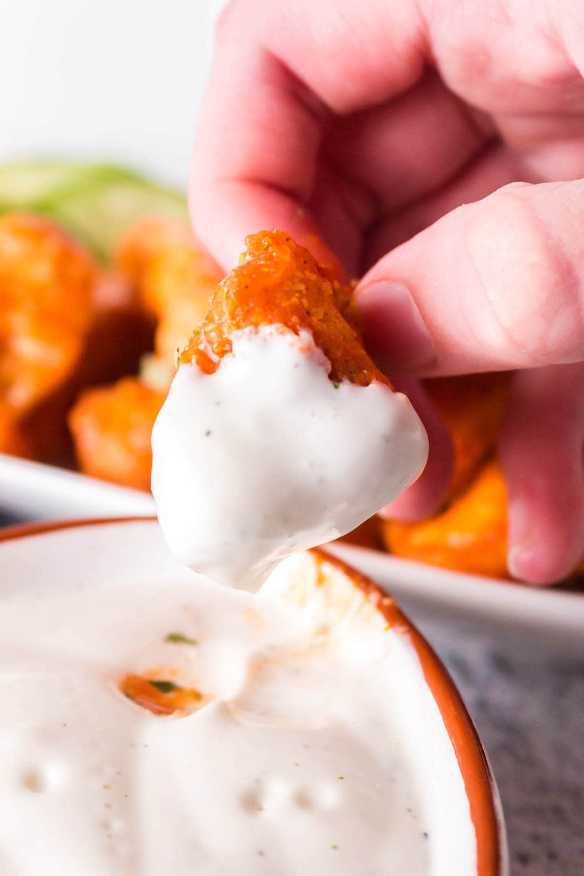 Chicken bites being dipped into ranch dressing.