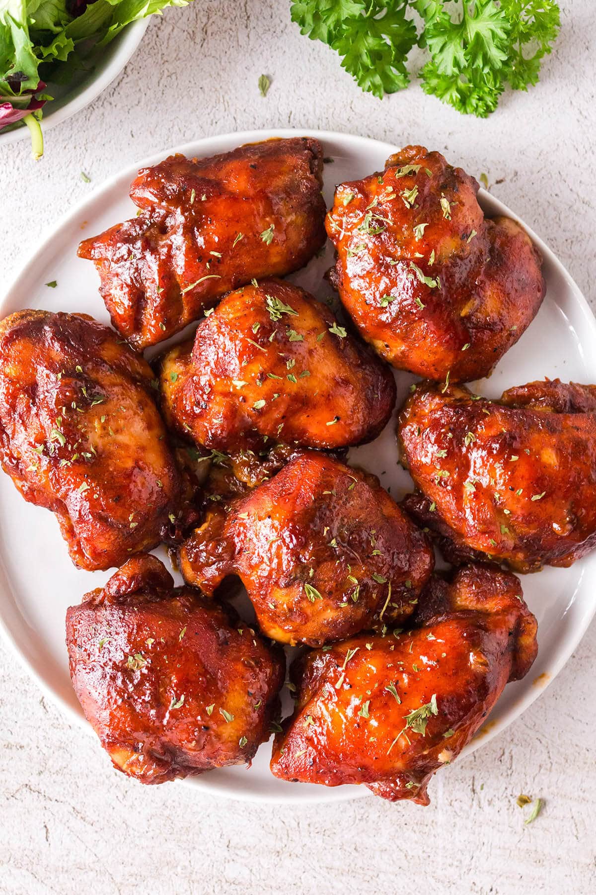 A platter filled with baked bbq chicken thighs.
