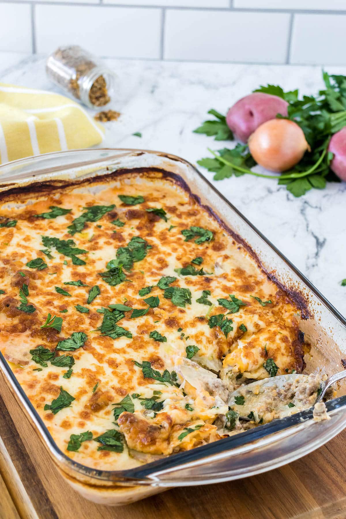 Cheesy Hamburger Potato Casserole in baking dish with serving spoon.