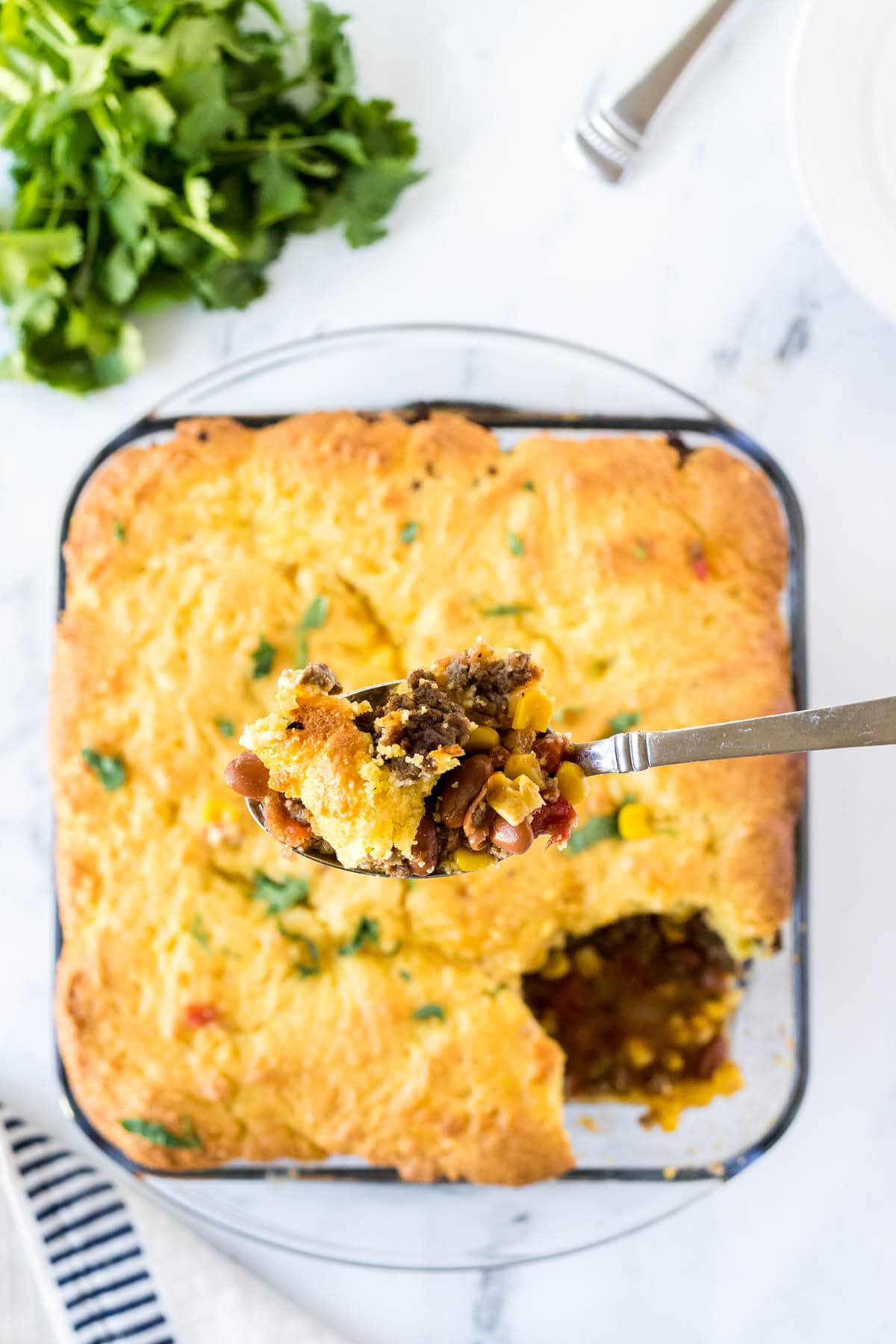 Cowboy Cornbread casserole in a baking dish with serving spoon.