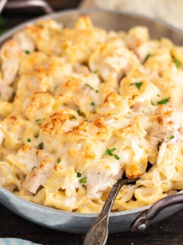 Cheesy pasta in pan with serving spoon.